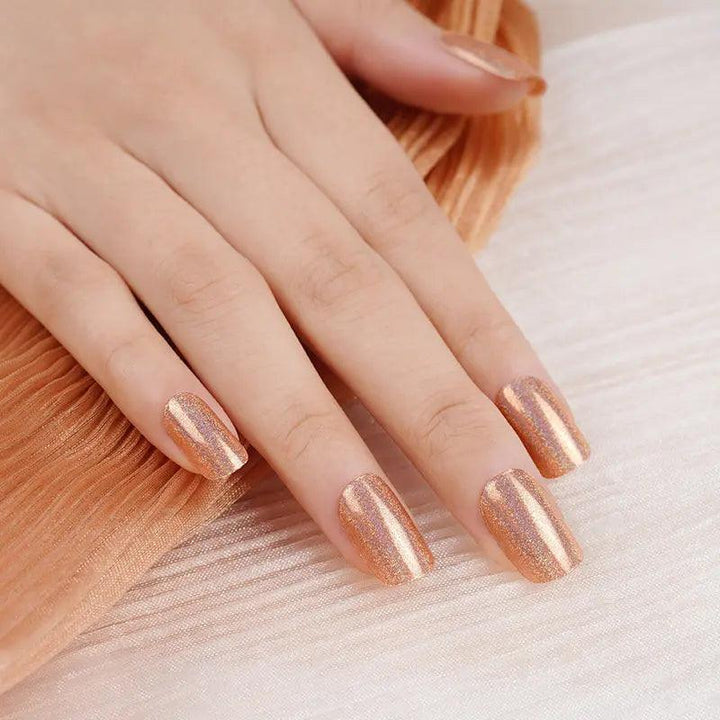 Copper gel nail wraps with fine rainbow shimmer and high-gloss metallic finish on light skin tone under warm indoor light.