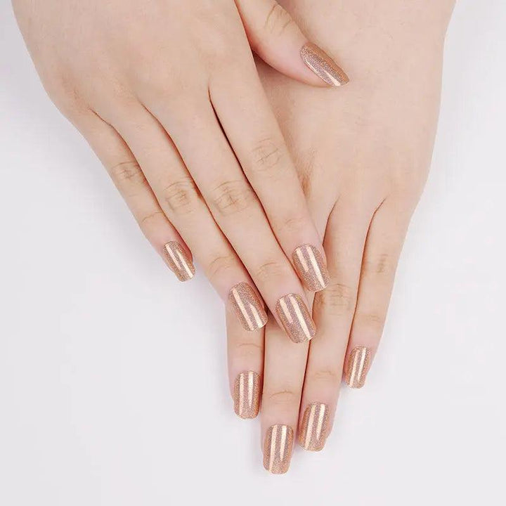 Amber metallic gel nail wraps with subtle rainbow shimmer on light skin tone, glossy reflective finish in daylight.