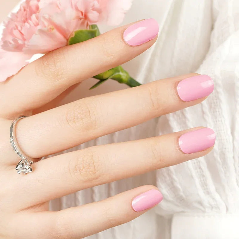 Semi-cured gel nail wraps in bright Barbiecore pink with a creamy high-gloss finish, shown on fair skin wearing a silver ring and white fabric.