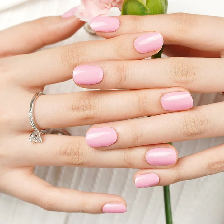 Semi-cured gel nail wraps in bold medium pink with a glossy shine, shown on light skin with silver jewelry and soft natural lighting.