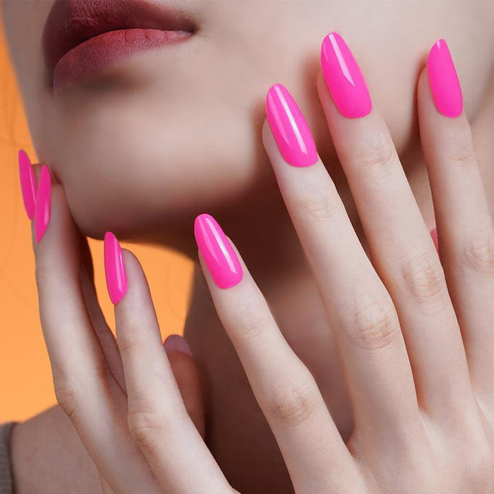 Neon pink gel nail wraps with glossy finish on light skin tone, styled in soft studio lighting.