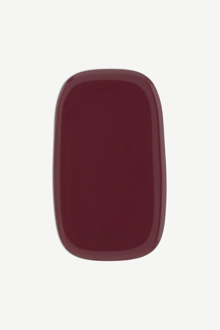 Close-up of a single burgundy red stick-on gel nail wrap with a smooth, glossy finish.