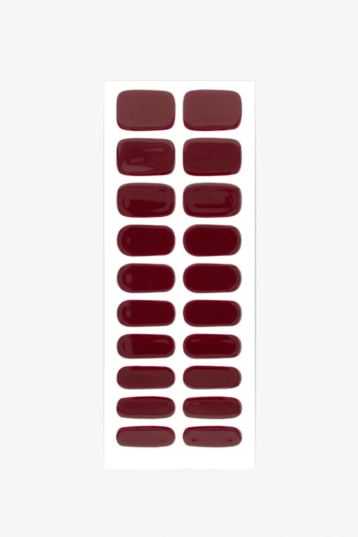 Set of burgundy red gel nail strips arranged on a white background.