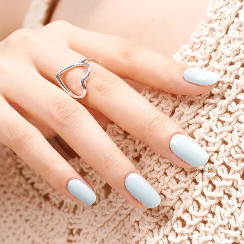 Semi-cured gel nail wraps in light teal with a crisp glossy finish, shown on light-medium skin wearing a silver heart ring and a crochet top.