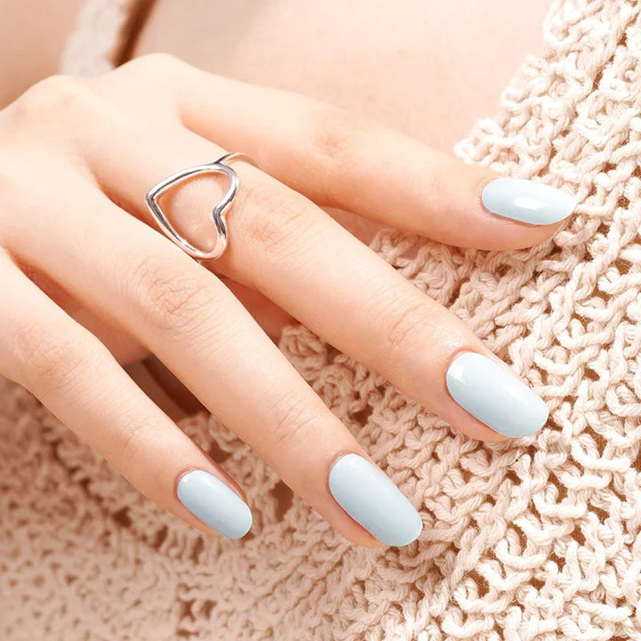 Semi-cured gel nail wraps in light teal with a crisp glossy finish, shown on light-medium skin wearing a silver heart ring and a crochet top.