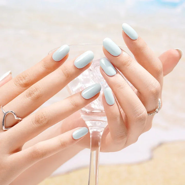 Semi-cured gel nail wraps in soft sea-foam teal with a glossy beach-glass glow, shown on light skin wearing silver rings in natural sunlight.