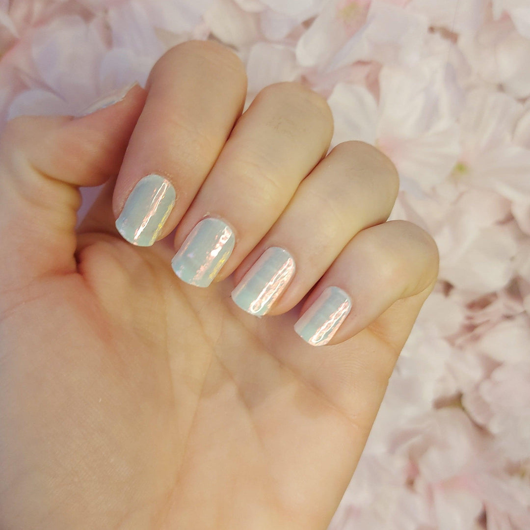 Chrome mint gel nail wraps with iridescent pearl shine on light skin tone, reflecting silver and aqua tones in soft light.