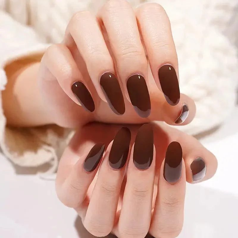 Dark coffee brown gel nail wraps with glossy surface on light skin tone, photographed under neutral daylight.