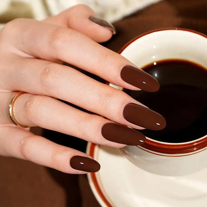 Espresso brown gel nail wraps with deep cocoa tone and high-shine finish on light skin tone, styled with gold jewelry in soft indoor light.