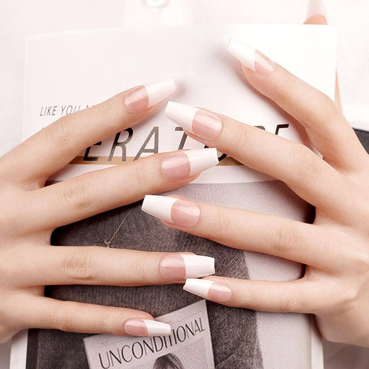Classic French tip semi-cured gel nail wraps with glossy nude base and crisp white tips on light skin tone with long nails.