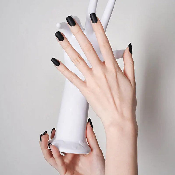 Matte black gel nail stickers with flat modern finish on light skin tone, styled against minimalist neutral tones.