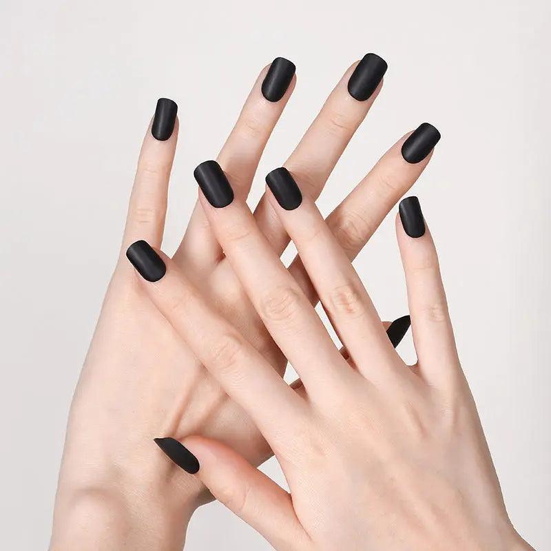 Matt black gel nail wraps with smooth flat finish on light skin tone, photographed in soft neutral lighting.
