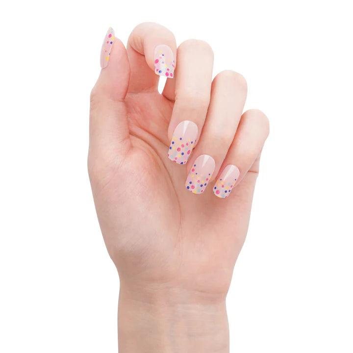 Semi-cured nude gel nail stickers with rainbow dots and high-gloss finish on light skin tone, photographed in warm light.