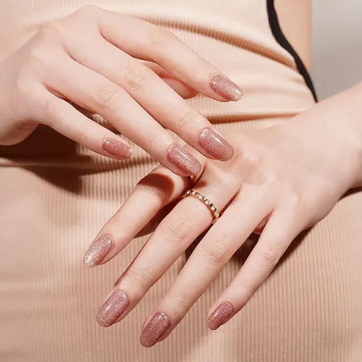 Rose gold shimmer gel nail wraps with cat-eye reflection and warm undertone on light skin tone, glossy and reflective.
