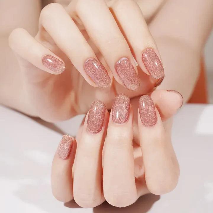 Warm rose gold gel nail wraps with metallic sheen and subtle cat-eye glow on light skin tone, smooth high-gloss finish.