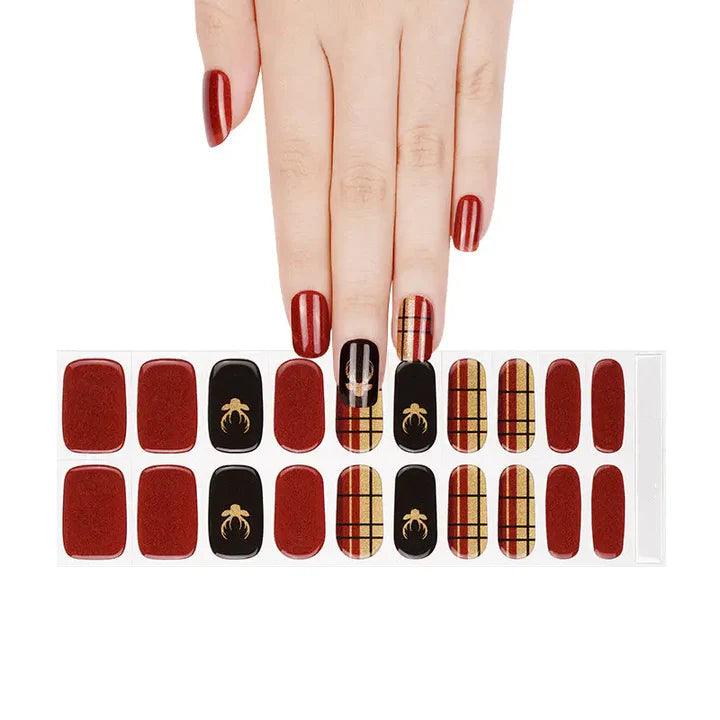 Sheet of deep red, black, and gold plaid gel nail wraps with glossy finish and holiday-inspired designs