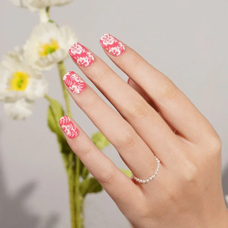 Semi-cured gel nail wraps in vibrant pink with white hibiscus flower patterns and a glossy finish, shown on light skin wearing a delicate pearl ring.