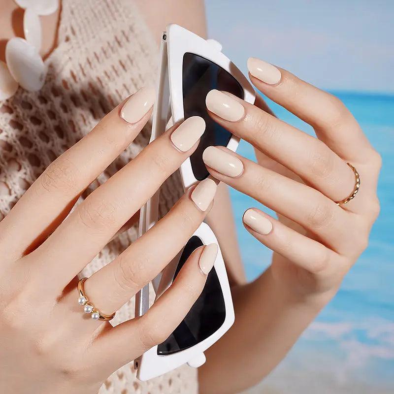 Creamy ivory gel nail wraps with smooth glossy surface on light skin tone, photographed in natural daylight.