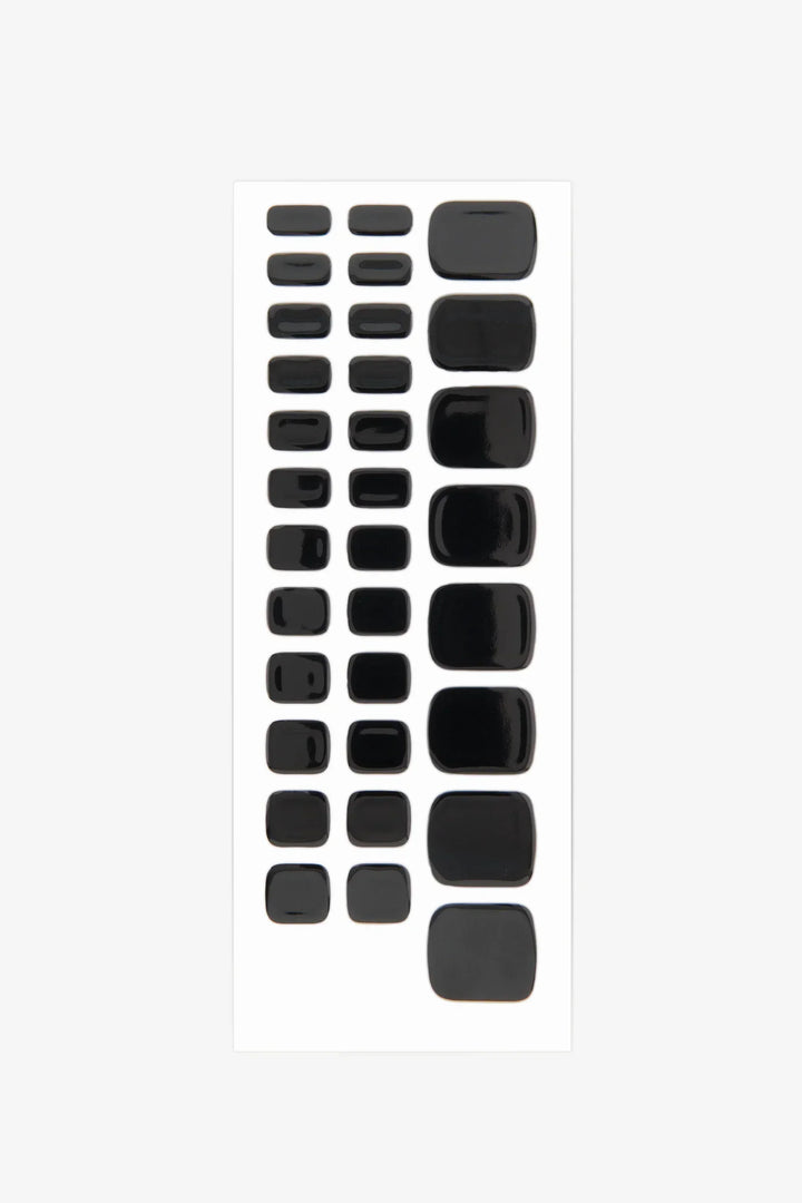 Sheet of black semi-cured gel toenail wraps with high-gloss finish and solid opaque color.