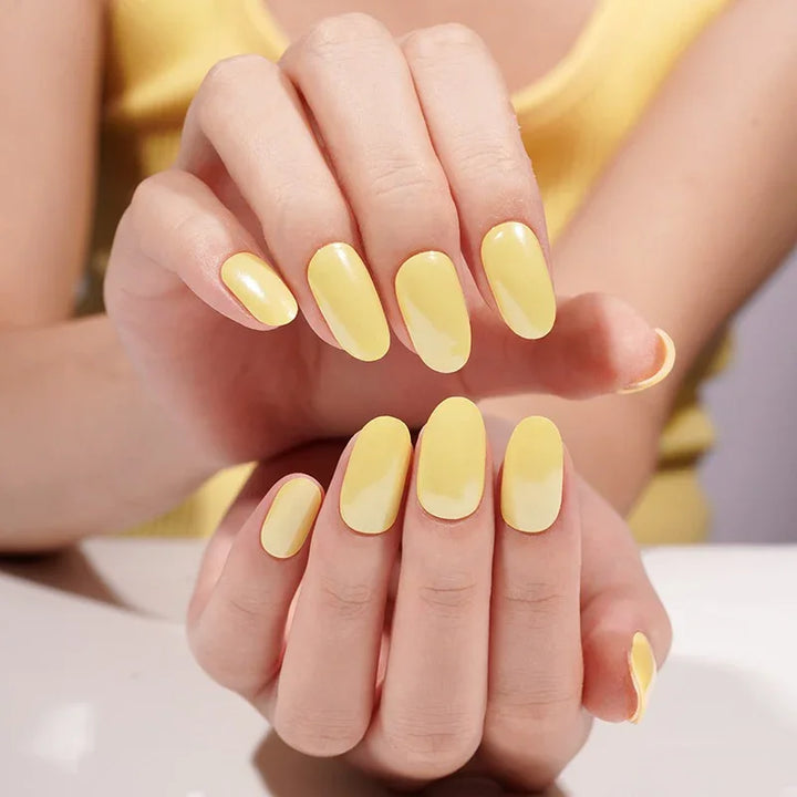 Semi-cured gel nail wraps in pastel lemon-yellow with a soft shimmer and smooth gloss, shown on fair skin.
