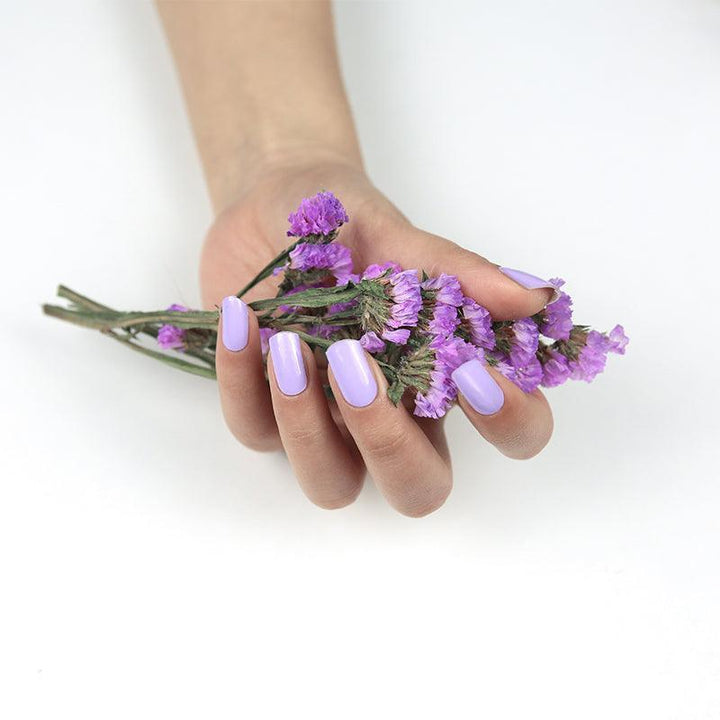 Medium-toned hand with pastel lavender glossy gel nail wraps.