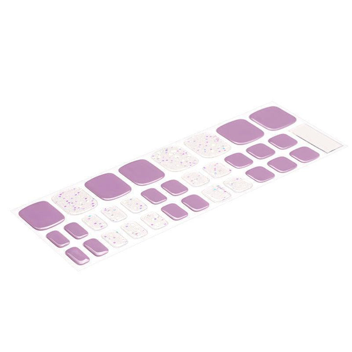 Sheet of lilac and transparent semi-cured gel toenail strips with scattered blue and purple holographic sprinkles and glossy finish.