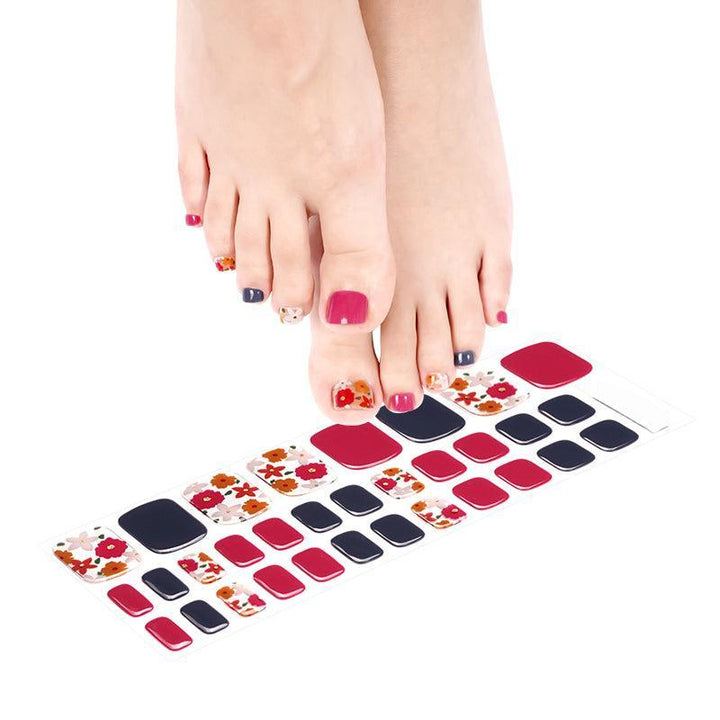 Sheet of red and navy floral gel toenail wraps featuring warm red and orange blossoms on transparent base.