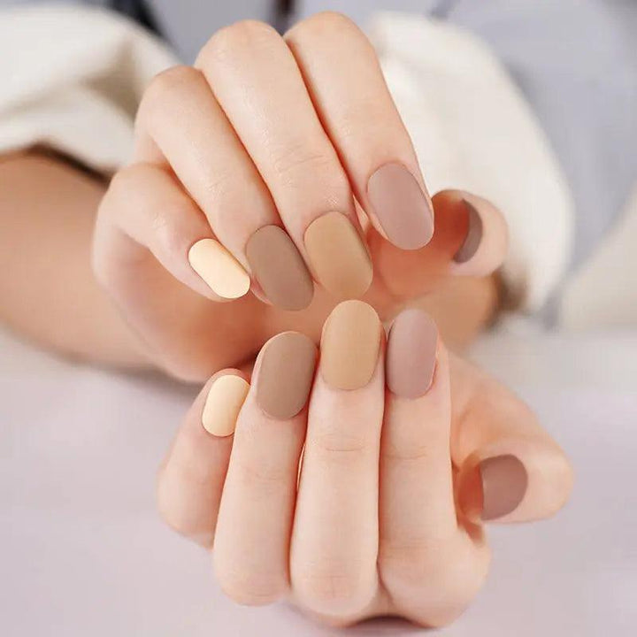 Neutral gradient gel nail wraps in matte finish, ranging from soft cream to sun-baked brown on light skin tone under warm indoor light.