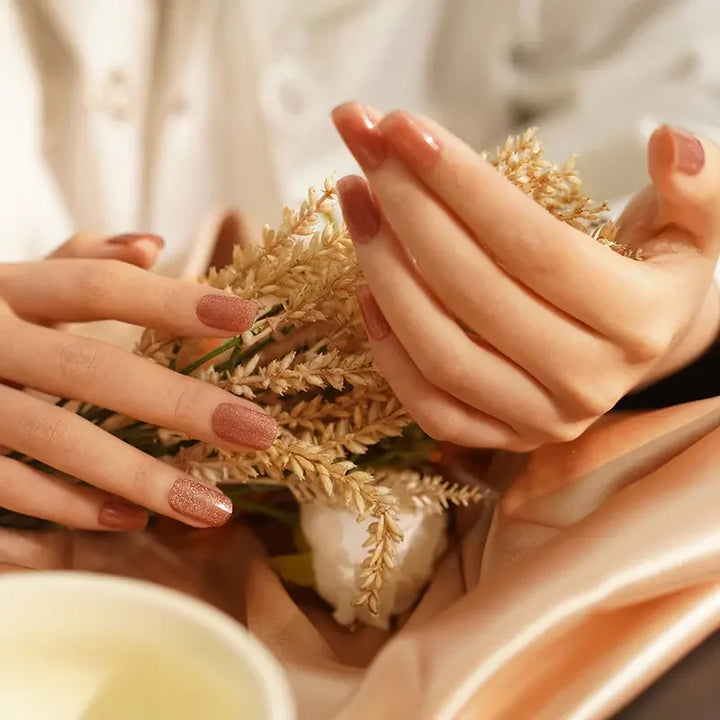 Semi-cured gel nail wraps in sheer golden beige with a radiant cat-eye effect, shown on light-medium skin in warm light.