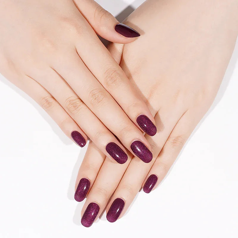 Semi-cured gel nail wraps in sheer plum purple with a soft shimmery cat-eye glow and glossy finish, shown on fair skin under neutral lighting.