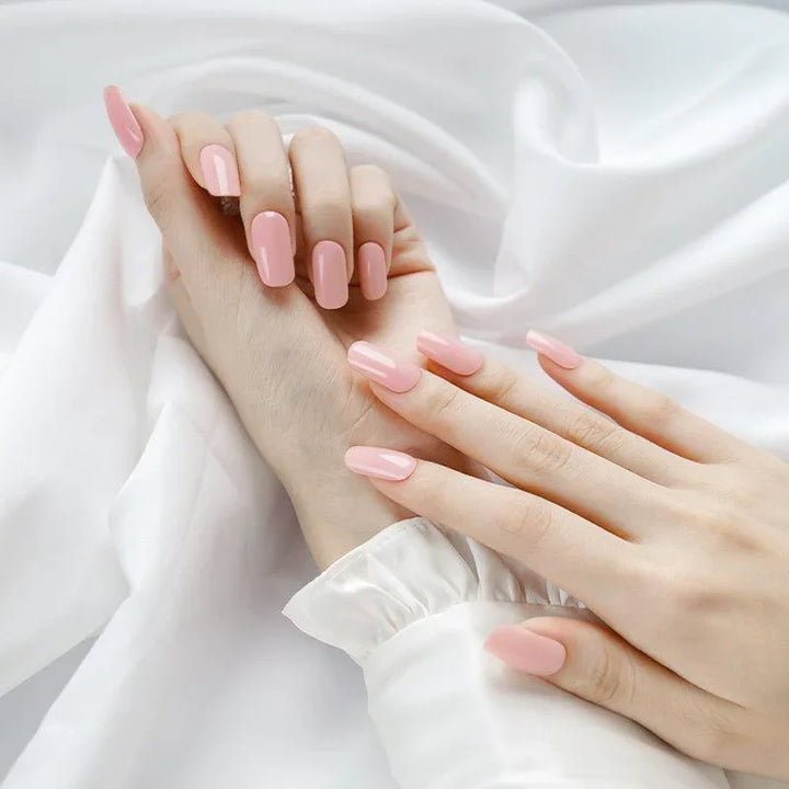 Soft peach gel nail wraps with glossy nude finish on light skin tone, styled with white sleeves.