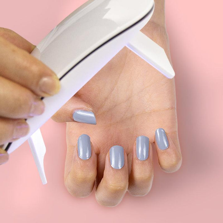 Stormcloud gray gel nail strips being applied on medium skin tone.