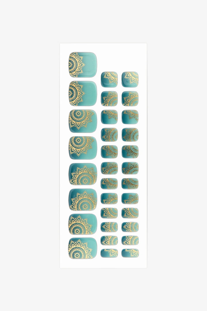 Sheet of semi-cured gel toenail wraps in teal-to-aqua gradient with intricate gold mandala detailing and a smooth, glossy surface.
