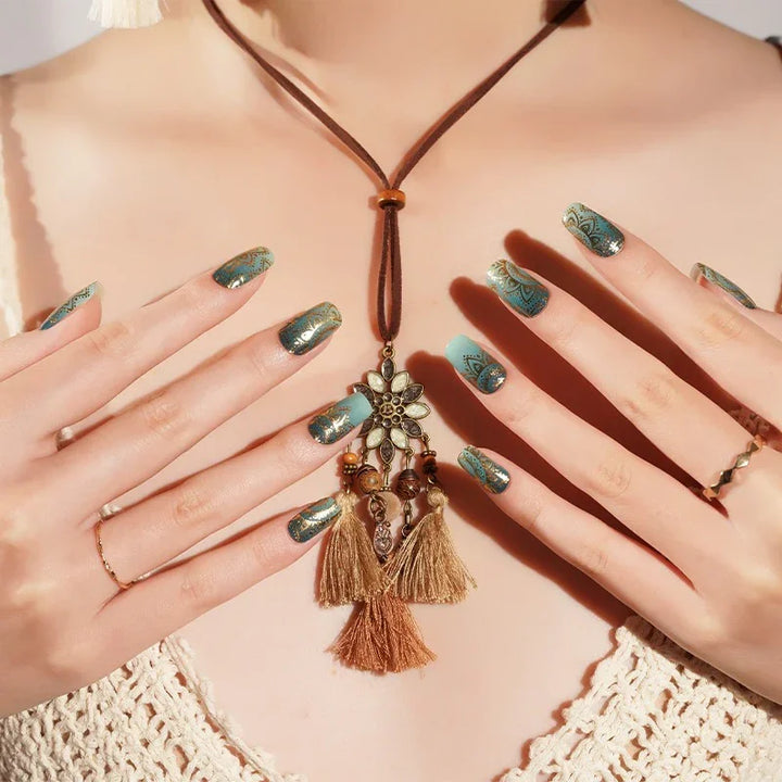 Semi-cured gel nail wraps in teal-to-aqua ombre with fine gold mandala patterns and a high-gloss finish, shown on light-medium skin wearing gold rings and a crochet top.
