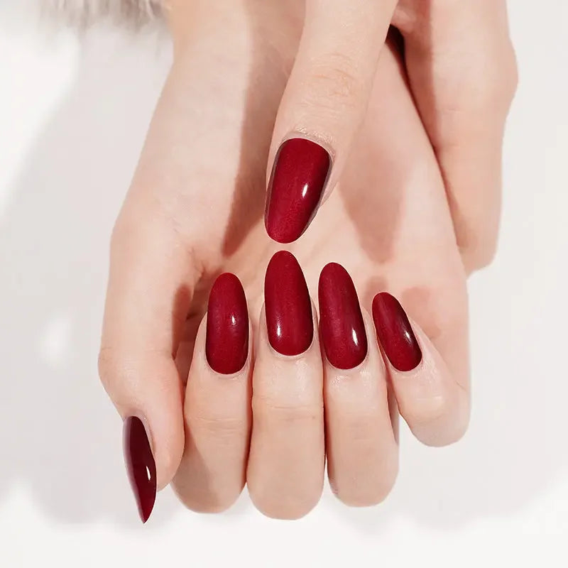 Semi-cured gel nail wraps in dark wine red with glossy cat-eye shimmer, shown on fair skin with a smooth high-shine finish.