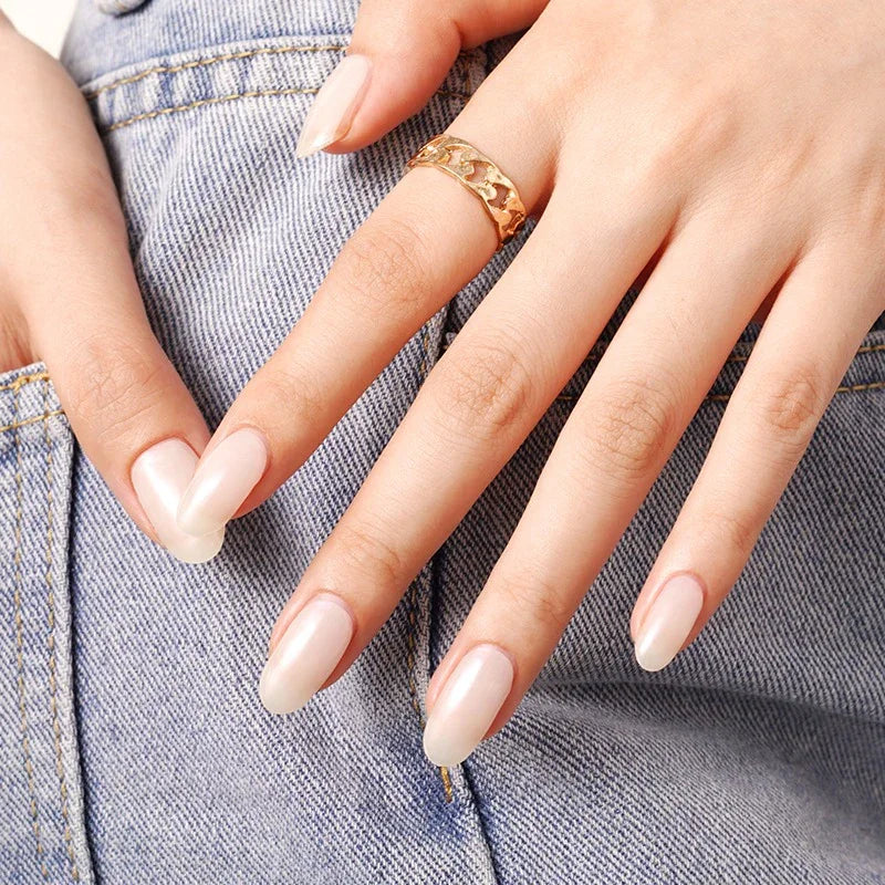 Semi-cured gel nail wraps in nude-beige with a pearly glow, shown on neatly manicured nails against light blue denim fabric.