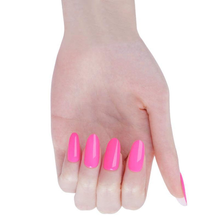 Bright pink stick-on gel nails with warm undertone and high-gloss finish on light skin tone, photographed in bright light.