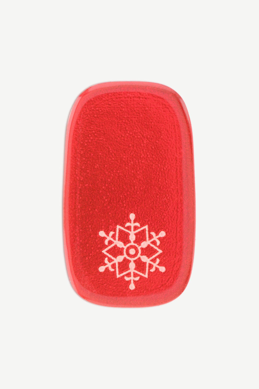 A macro image of a red stick-on gel nail with white snowflake accent design and glossy surface, shown on white background.
