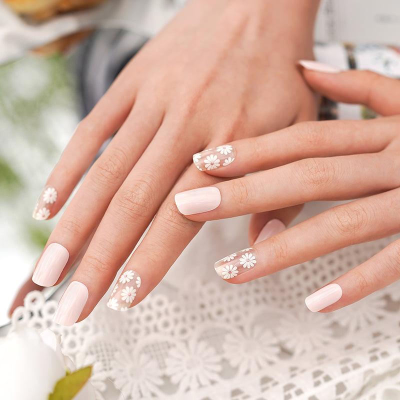 Soft pink semi-cured gel nail wraps with white daisy flower details and high-gloss shine on light skin tone.