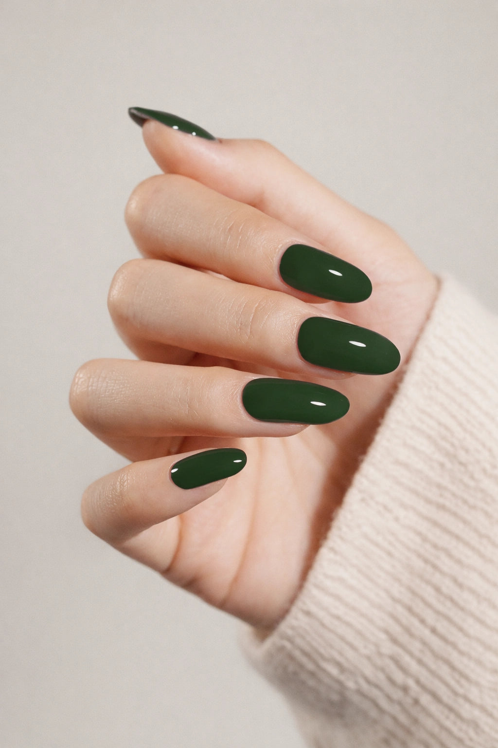 Deep Forest semi-cured gel nail stickers with a deep emerald-green shade and a smooth high-gloss finish. Shown on light skin and photographed under soft studio lighting against a neutral beige background.