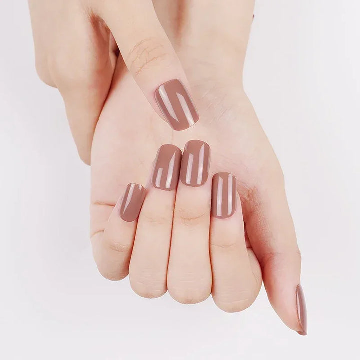 Close-up of hands with Dusk gel nail wraps in a semi-transparent, muted mocha hue, highlighting the glossy, rose-brown finish.