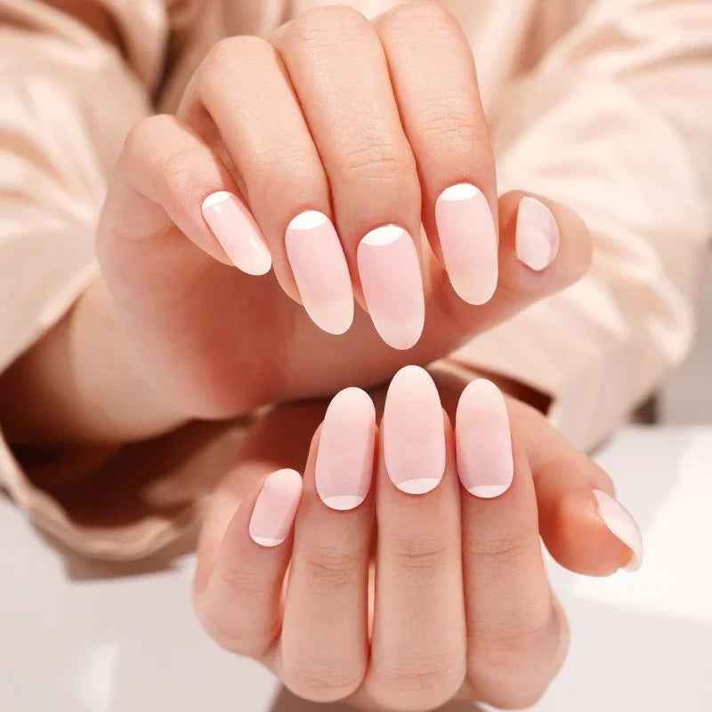 Close-up of French Moon gel nail wraps — glossy milky pink nails with crescent-shaped bases, elegant minimalist manicure style.