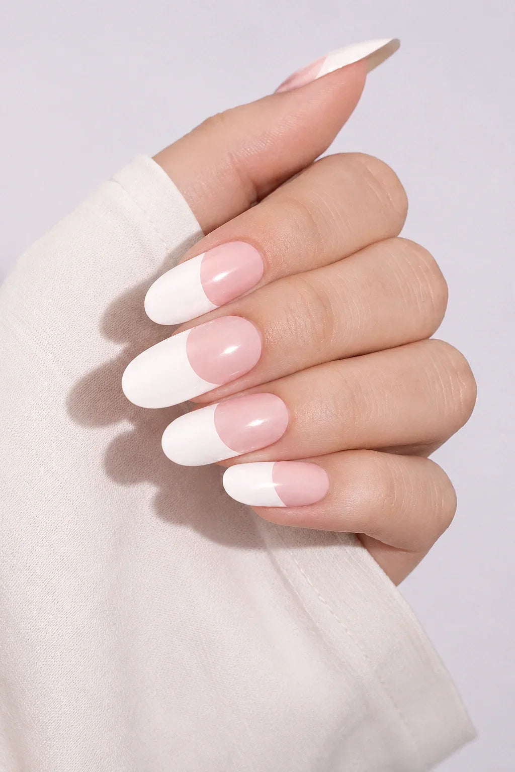 UV-free gel nail wraps with a classic French tip design featuring soft blush pink bases and crisp white tips with a glossy finish, shown on light skin.