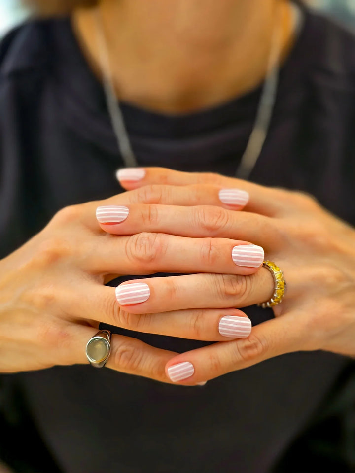 Close-up of hands with pink nail polish and rings on a blurred background
