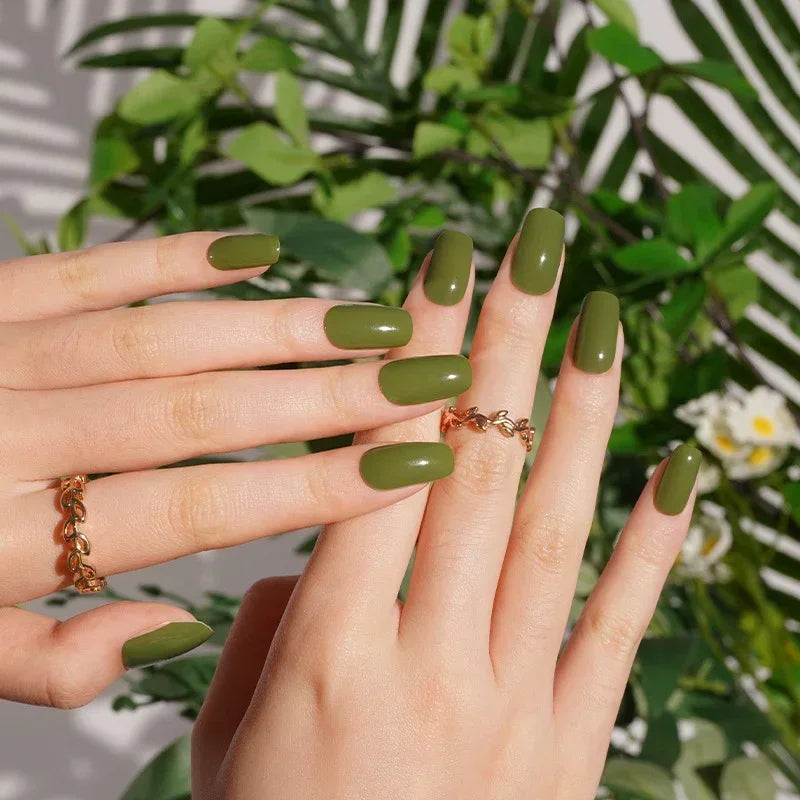 Semi-cured gel nail wraps in deep olive green with a glossy finish, shown on medium skin tone wearing gold jewelry.