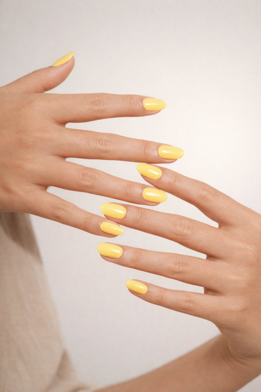 Lemon Sorbet semi-cured gel nail stickers, worn on light skin with a creamy pastel yellow shade and glossy finish, photographed under soft studio lighting with a minimal neutral backdrop.