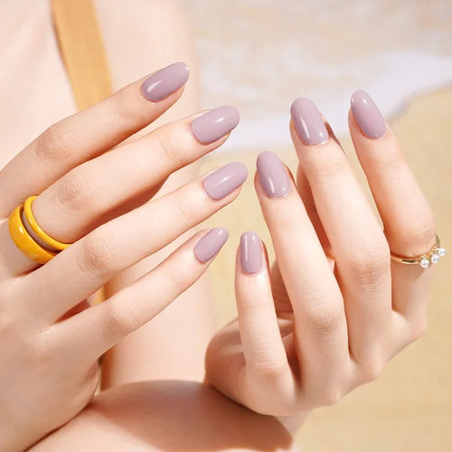Semi-cured gel nail wraps in soft mauve with blended rose and lavender tones, shown on light-medium skin wearing gold rings in warm sunlight.