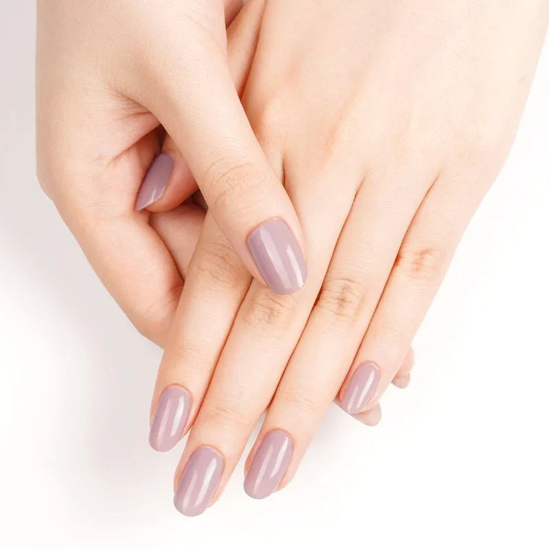 Semi-cured gel nail wraps in soft purple-taupe with a creamy gloss, shown on light skin with neatly shaped nails.