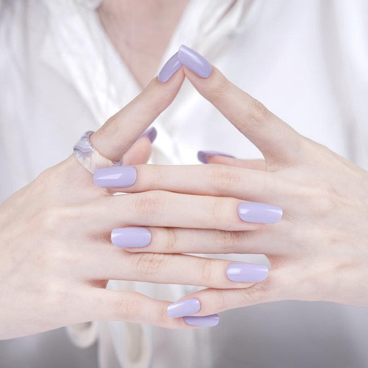 Soft lavender gel nail wraps with glossy surface on light skin tone, styled with white clothing.