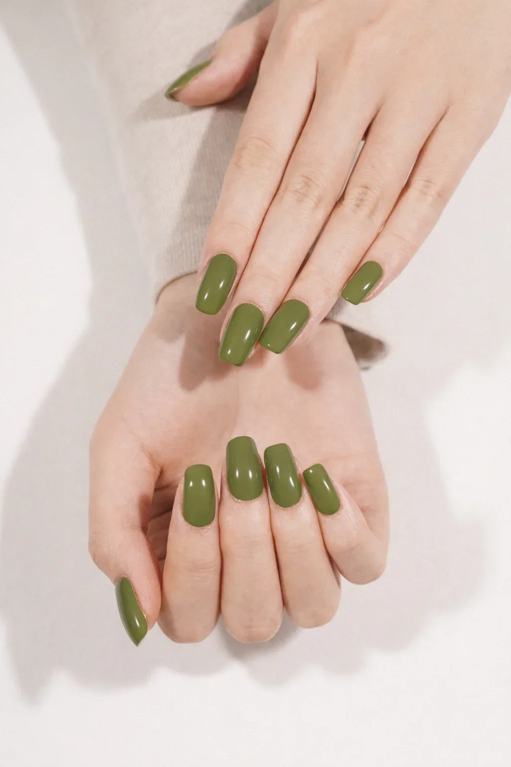 Semi-cured gel nail wraps in earthy olive green with a creamy, reflective gloss, shown on light skin.